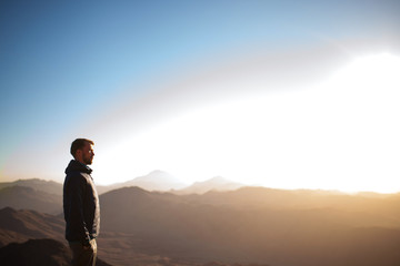 Man stands on Mount Sinai and looks at sunrise.