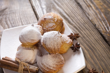 Delicious eclairs sprinkled with icing sugar, stand on a wooden table. Copy spase.