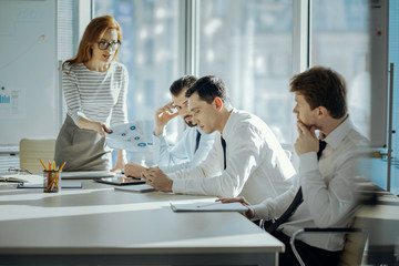 Unsatisfied with performance. Pretty young female boss holding printouts with inaccurate research...