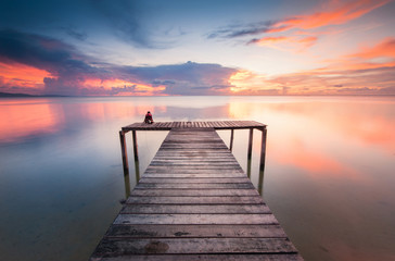 Naklejka na ściany i meble wooden jetty toward horizon during sunset with reflection.