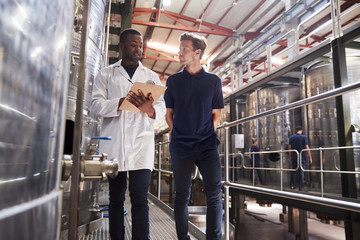 Two male staff members make an inspection at a wine factory