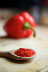 Paprika spice powder is poured on a wooden boat lying on a village Board.