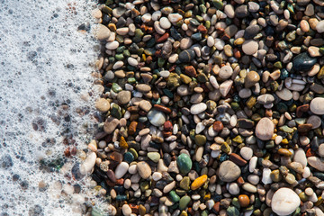 multi-colored pebbles on the beach, washed by waves