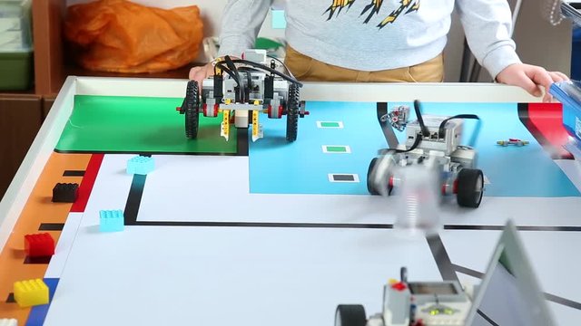 Closeup view of kids testing their just built computerized robots on special table at robotics lesson. Children construct and programm robots. Real time full hd video footage.