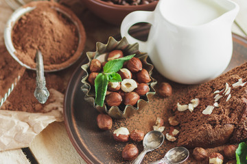 Piece of chocolate cake, mint leaves, hazelnuts and jar with milk