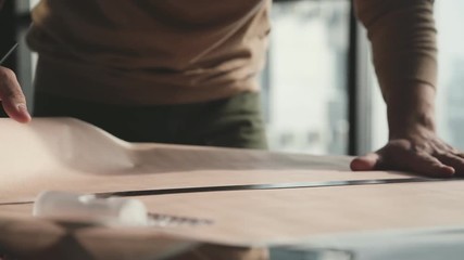 Architect's desk: drawings, tape measure, ruler and other drawing tools. Engineer works with drawings in a bright office, close-up. Insturments and office for designer. Male hands draw with a pencil. - Powered by Adobe