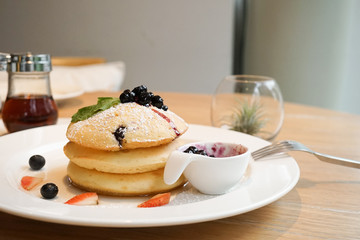 Pancakes for breakfast. Three thick pancakes served with fresh blueberries and strawberries.