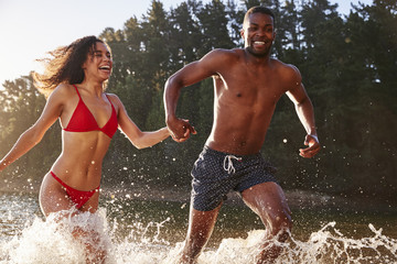 Young mixed race couple running and splashing in a lake