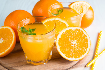 Close-up of a glass of orange juice with oranges fruits on wooden and stone background. Vitamins and minerals. Healthy drink and beverage concept.