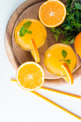 Close-up of a glass of orange juice with oranges fruits on wooden and stone background. Vitamins and minerals. Healthy drink and beverage concept.