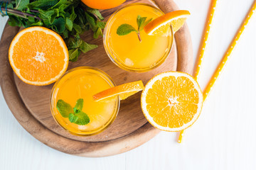 Close-up of a glass of orange juice with oranges fruits on wooden and stone background. Vitamins and minerals. Healthy drink and beverage concept.