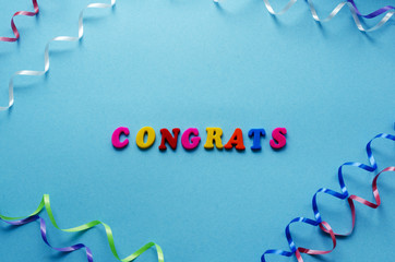 word 'congrats' from magnetic letters and serpentine on blue paper background