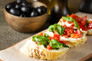 Tomato and cheese fresh made bruschetta. Italian tapas, antipasti with vegetables, herbs and oil on grilled ciabatta and baguette bread.