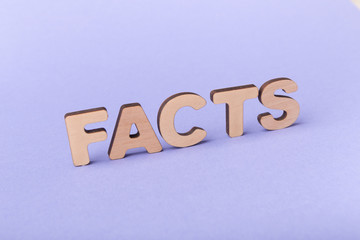 Word facts spelled with wooden letters on violet background