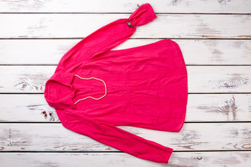 Pink women's blouse with accessories on wood backgroud. Top view shirt, balls necklace, bracelet,...