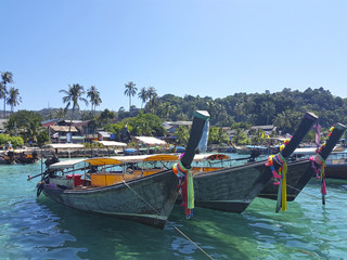Fleet of wooden boats with colorful ribbons docked near picturesque sunny beach.