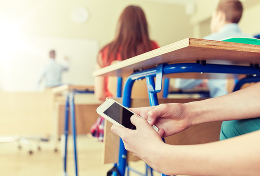 student boy with smartphone texting at school