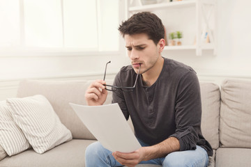 Young tired businessman reading report at home