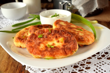 Golden cottage cheese pancakes syrniki and sour cream sauce on a white plate