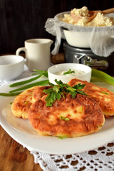 Golden cottage cheese pancakes syrniki and sour cream sauce on a white plate