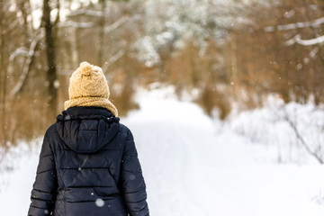 Girl walking in winter snow, woman in black jacket back view in the forest