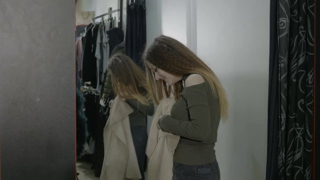 Beautiful popular woman shopping trying clothes in the fitting room and looking in the mirror