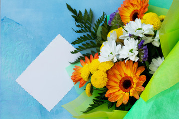A wedding story or background Mother's Day. Bouquet of gerbera with chrysanthemums and sweets on a blue stone background or concrete. Free space for your congratulations, top view flat lay background.