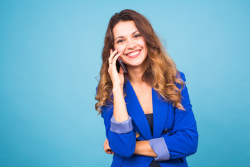 Fototapeta premium Happy smiling successful businesswoman with cell phone, on blue background