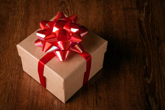 One festive gift box with a red bow on a wooden table