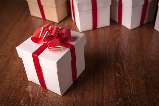 One white festive gift box with a red bow against a background of white boxes