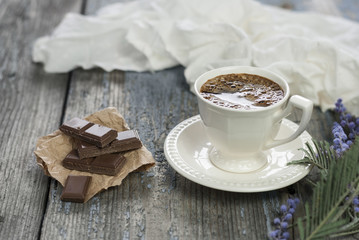 Coffee cup and chocolate on wooden table texture.