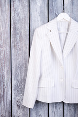 White suit jacket on hanger. Dark wooden background. Top view.