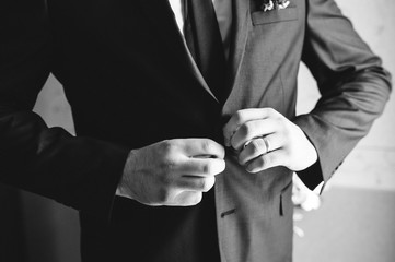 Obraz premium the groom is putting on his wedding suit, black and white photo