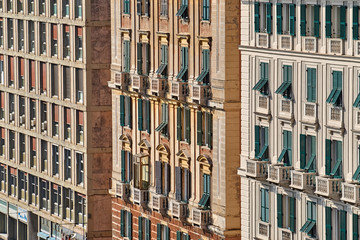 Three buildings with a similar pattern made of windows, balconies and window shutters in the street of Genoa, Italy © Wiktor