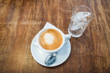 Cafe culture: a cup of coffee and a glass of ice on a table at a cafe
