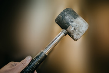 A hand holding hammer with a gold background