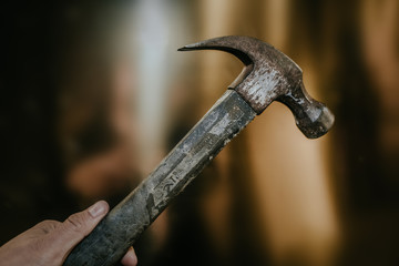 A hand holding hammer with a gold background