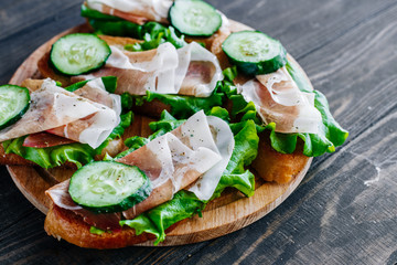 Sandwiches with cucumbers and prosciutto on the board