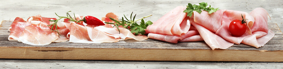 Italian prosciutto crudo or jamon with rosemary. Raw ham - obrazy, fototapety, plakaty
