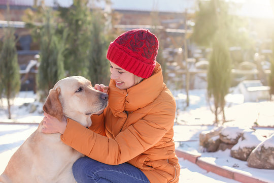 Woman hugging cute dog outdoors on winter day. Friendship between pet and owner