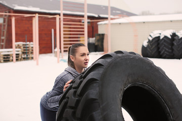 Naklejka na ściany i meble Young sporty woman flipping heavy tire, outdoors