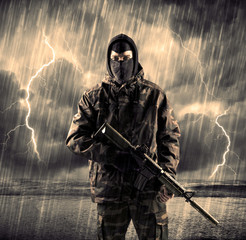 Dangerous armed terrorist with mask and gun in a thunderstorm with lightning