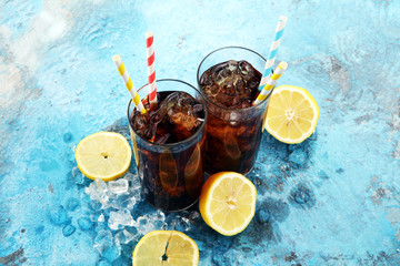 Softdrink with ice cubes, lemon and straw in glass.