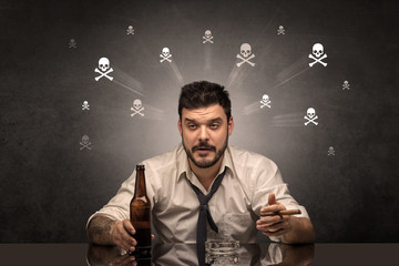 Drunk man sitting at table with skulls concept