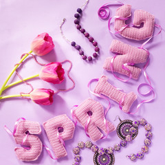 tulip floweres and spring word from knitted letters on pink paper