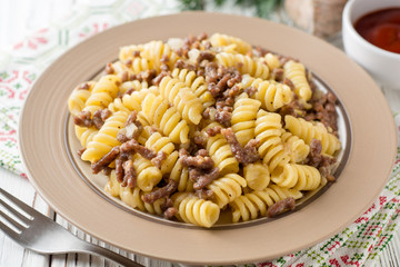 Fusilli pasta with minced meat and onion in navy-style on white wooden table. Makarony po-flotski, Russian dish.
