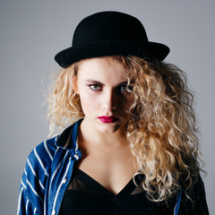 Young beautiful female in hat is posing in the studio