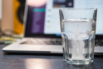 glass of water with aspirin. laptop on background. overloaded with office work