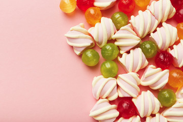 Border of marshmallows and colourful sweets on pink background