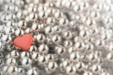 Little heart placed on silver and gold necklace.